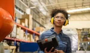 A young female worker is controlling a mechanical robot.