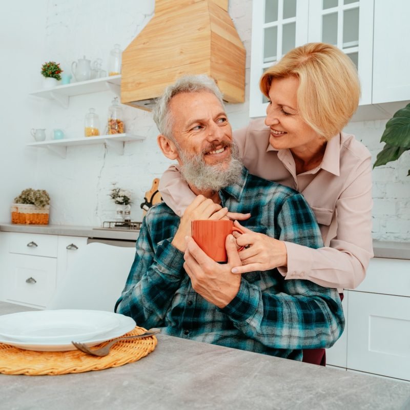 Retired husband and wife hug each other at home